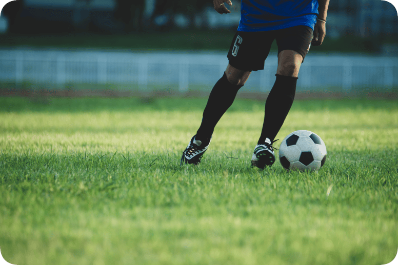 "Jugador de fútbol en acción controlando el balón sobre el césped verde de una cancha