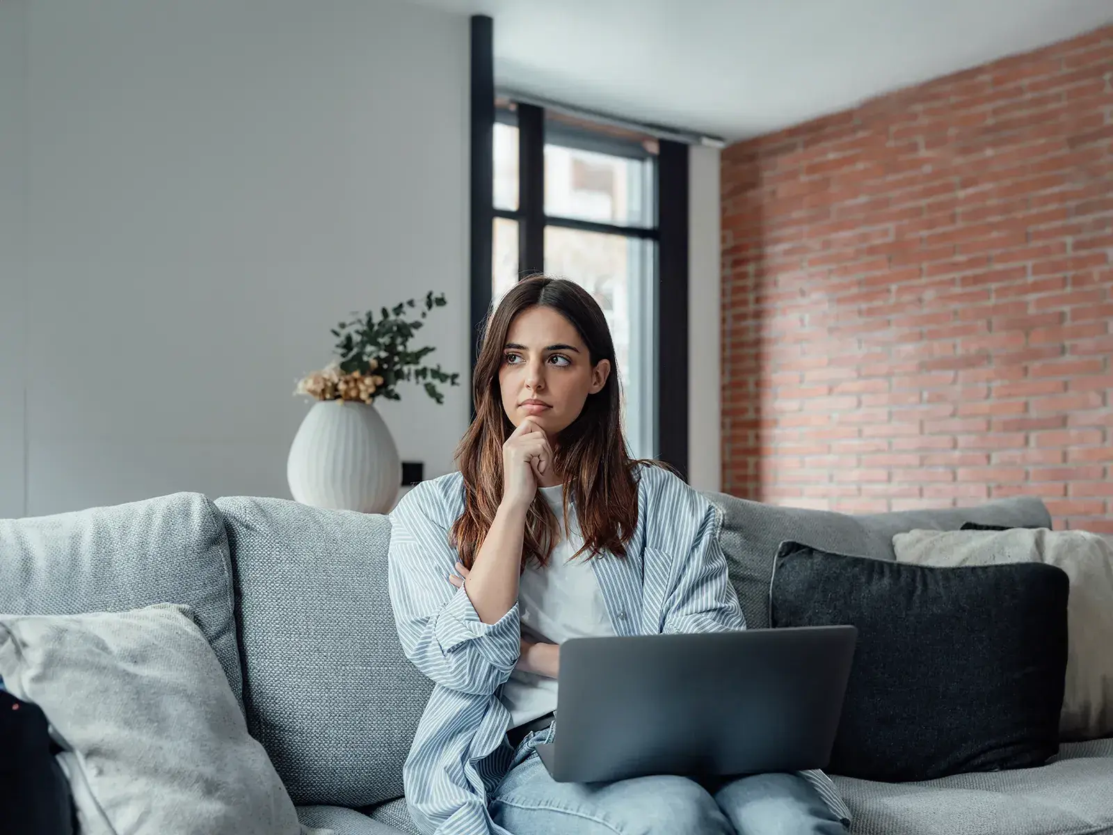 Mujer joven pensativa evaluando qué comprar, con fondo claro y expresión de análisis financiero. Representa la libertad de decisión tras consolidar deudas con MultiMoney.