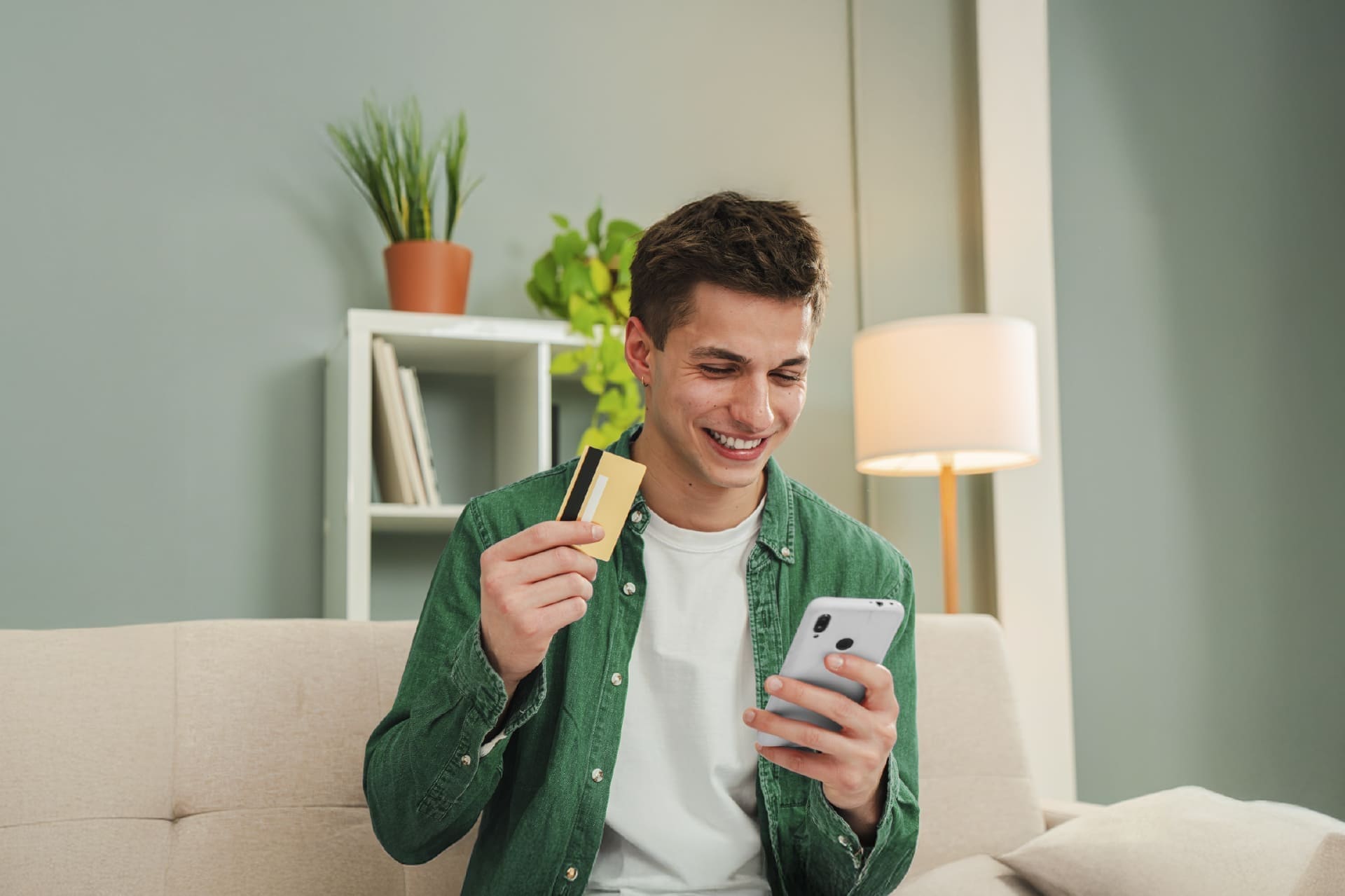 Joven revisando su celular mientras sostiene una tarjeta de crédito, reflejando control financiero y uso inteligente del crédito revolvente